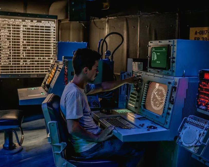 Empty control room with glowing monitors and vacant operator chairs at night.
